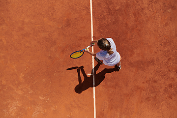 Image showing Top view of a professional female tennis player serves the tennis ball on the court with precision and power