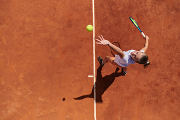 Image showing Top view of a professional female tennis player serves the tennis ball on the court with precision and power