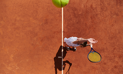 Image showing Top view of a professional female tennis player serves the tennis ball on the court with precision and power