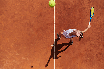 Image showing Top view of a professional female tennis player serves the tennis ball on the court with precision and power