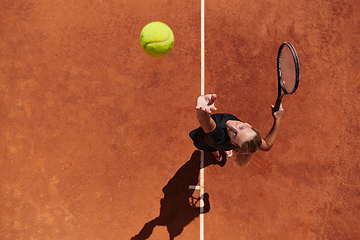 Image showing Top view of a professional female tennis player serves the tennis ball on the court with precision and power