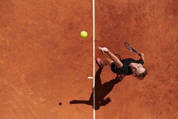 Image showing Top view of a professional female tennis player serves the tennis ball on the court with precision and power