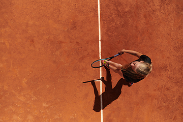 Image showing Top view of a professional female tennis player serves the tennis ball on the court with precision and power