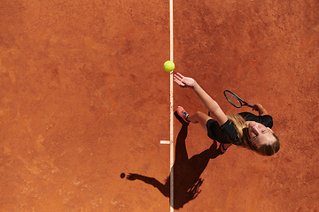 Image showing Top view of a professional female tennis player serves the tennis ball on the court with precision and power