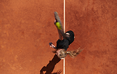 Image showing Top view of a professional female tennis player serves the tennis ball on the court with precision and power