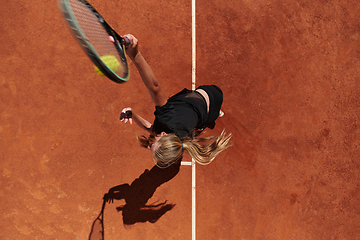 Image showing Top view of a professional female tennis player serves the tennis ball on the court with precision and power