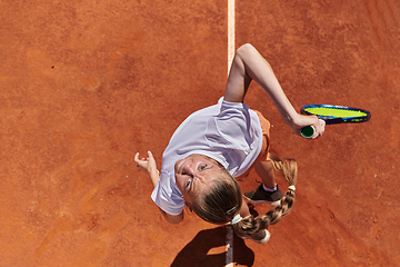 Image showing Top view of a professional female tennis player serves the tennis ball on the court with precision and power