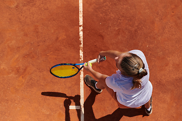 Image showing Top view of a professional female tennis player serves the tennis ball on the court with precision and power