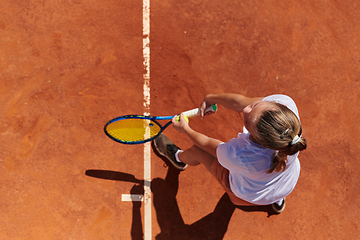 Image showing Top view of a professional female tennis player serves the tennis ball on the court with precision and power