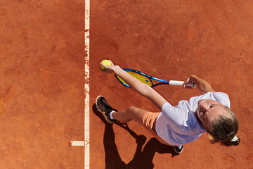 Image showing Top view of a professional female tennis player serves the tennis ball on the court with precision and power