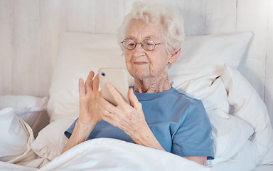 Image showing Phone, bed and senior woman in nursing home surfing internet, social media or nostalgic photographs with happy memories. Communication, technology and grandma in bedroom of retirement home with smile