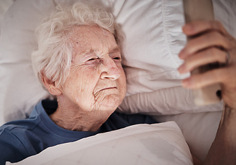 Image showing Phone, face and morning with a senior woman waking up in bed in the bedroom of her retirement home. Contact, social media and early with a mature female checking her mobile messages in the house