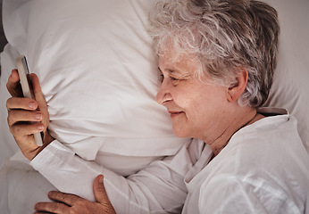 Image showing Smile, phone and senior woman in bed, text and read social media, message and relax in her home. Happy, elderly lady and online communication after wake up, browse and email on smartphone in bedroom