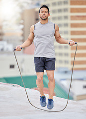 Image showing Jump, rope and man on a rooftop for fitness training, exercise and skipping for cardio in the city. Jumping, focus and Asian athlete with energy for an urban workout for wellness, body and health