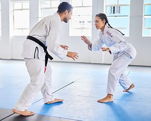 Image showing Karate, martial arts and man and woman fight, battle or practice fighting skill during training, workout or fitness challenge. Coach, dojo class and girl learning self defense from taekwondo teacher