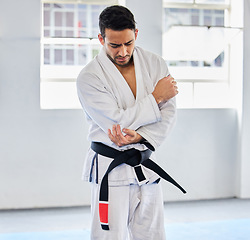 Image showing Karate, arm pain and man with injury in dojo, healthcare and fighting. Sports, fitness and martial arts fighter in India with hand elbow sports injury and medical emergency in fighting gym or studio.