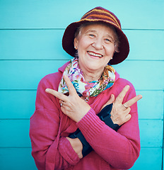 Image showing Peace sign, hip hop and portrait of a senior woman in the city with energy, smile and urban fashion. Cool, trendy and elderly grandma with emoji hand in retirement on a blue background or wall