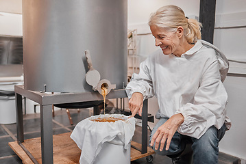 Image showing Happy, smile and beekeeper working with honey for eco friendly, organic and natural production at warehouse. Business owner with happiness for the process of sweet food from a machine in agriculture