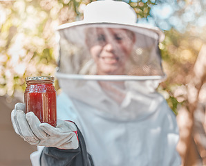 Image showing Hand, honey and jar with a woman beekeeper working in the countryside in the production of a natural product. Farm, agriculture and sustainability with a female farmer holding a honeyjar outdoor