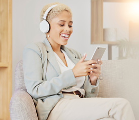 Image showing Business woman, headphones and phone streaming of music or video in a office with technology. Black woman smile on social network, music or web app on a sofa listening to funny podcast