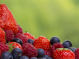Image showing Pile od strawberries, blueberries, raspberries on green background