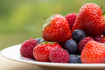 Image showing Pile od strawberries, blueberries, raspberries on green background