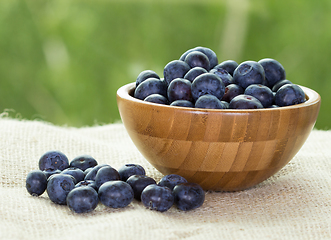 Image showing Blueberries in a wooden bowl on a rustic table with green background