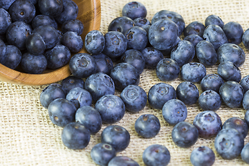 Image showing Blueberries in a wooden bowl scattered on a rustic table