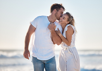 Image showing Happy, love and couple at the beach while on a vacation for romance, honeymoon or relaxation. Happiness, kiss and young man and woman walking by the ocean while on romantic holiday adventure together