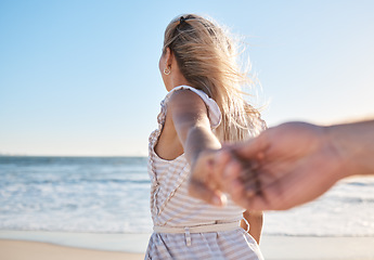 Image showing Hands, love and walking with a couple on the beach during summer vacation for romance or bonding. Sea, travel and holding hands with a woman leading her man on a walk by the ocean water on holiday