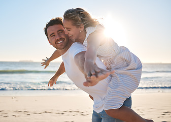 Image showing Happy, couple and piggyback walk on the beach for love, travel or summer vacation bonding together in the outdoors. Man carrying woman on back with smile enjoying playful fun time walking by the sea