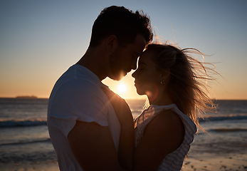 Image showing Sunset, silhouette and couple with love at the beach, affection and quality time on a holiday in Bali. Dark, sunrise and man and woman with care, hug and peace by the tropical water on vacation