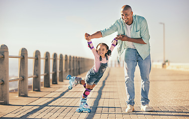 Image showing Skating, learning and father holding hands of his child while teaching her on the beach promenade. Family, love and dad helping his young girl kid for support, balance and care to outdoor rollerskate