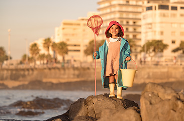 Image showing Girl, fishing and beach adventure for freedom, peace and learning skill development. Child, happy and ready with fishing net, bucket and fun outdoor activity, portrait and happiness in sunshine