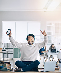 Image showing Music, phone and businessman with headphones on desk listening to audio, track and radio in office. Freedom, happiness and man sitting on table in corporate workplace with mockup smartphone screen