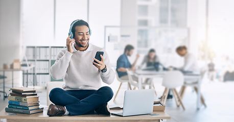 Image showing Man, music headphones and relax at startup, office or workplace for digital marketing with smile. Happy worker, video and sitting on table with smartphone, laptop and reading social media at company