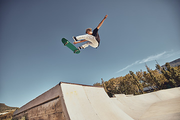 Image showing Sports, skateboarding and skater in air at park doing tricks, skating and having fun in urban town. Fitness, freedom and man do action skills, jumping and cool movement for sport, hobby and exercise