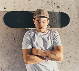 Image showing Skateboard, fashion or man with arms crossed in city skate park for stunt training, hobby exercise or freestyle skating in top view. Portrait, skater or skateboarder lying on concrete ground or floor