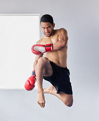 Image showing Muay thai, jump and fitness with man kick boxing for training, martial arts and and sports fight. Action, workout and energy with athlete and boxing gloves for mma, champion and exercise in dojo gym