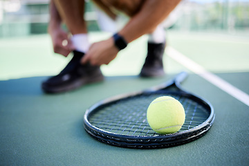 Image showing Tennis ball, racket and man tie shoes on tennis court preparing for competition, game or match. Exercise, fitness and tennis player getting ready for practice, training or workout outdoors on field.