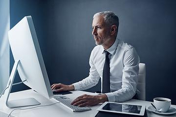 Image showing Typing auditor, computer and elderly man in studio, working and isolated on a dark background mockup. Focus, writing or serious executive at desktop for reading email, research or business accountant