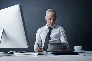 Image showing Tablet, accountant and senior man writing in studio isolated on a dark background mockup space. Technology, notes and serious manager at desk to work on audit project, reading email or business app.