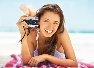 Image showing Portrait, camera and a woman tourist on the beach during summer for a holiday or luxury vacation. Ocean, bikini and smile with a happy young female photographer on the sand to relax by a coastal sea