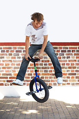 Image showing Unicycle, sports and man jumping in city for exercise, training or workout on wall mockup space. Action, cycling and performance of stunt in street for trick, travel and eco friendly transportation.