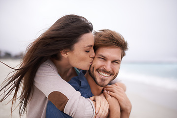 Image showing Woman kiss man, happiness and beach with holiday, travel and love with care and trust outdoor. Freedom, affection and fun with couple in nature, vacation and smile with support and hug by the ocean