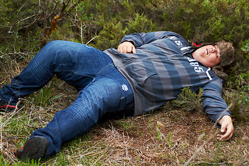 Image showing Drunk, sleeping and hangover with a plus size man lying outdoor on the grass or ground after a party. Festival, alcohol and tired with a young male person asleep on a field or lawn in the morning