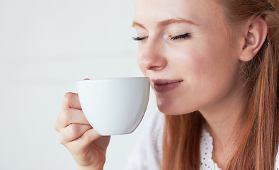 Image showing Face of woman smell her cup of coffee in a studio for a scent in the morning on a weekend. Calm, relax and female model enjoying the aroma of a cappuccino, caffeine or latte by a white background.