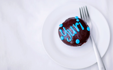 Image showing Cupcake, chocolate cake and dessert on a plate for a birthday celebration with a name or work. Food, unhealthy eating and bakery sugar product on a table to celebrate at a party for Yuri from above