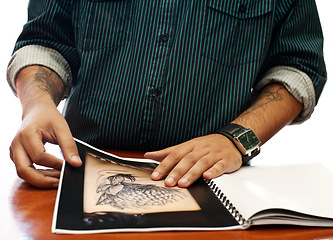 Image showing Hands, search and book for a tattoo design, picture choice or inspiration for body art at a studio. Closeup, paper and a man with a check on photos for ink, creativity and decision for tattoos