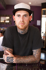 Image showing Tattoos, creative and portrait of a man with tattoos standing by the counter of his artistic studio. Confident, cool and punk man with a edgy, funky and body art or ink creativity business store.